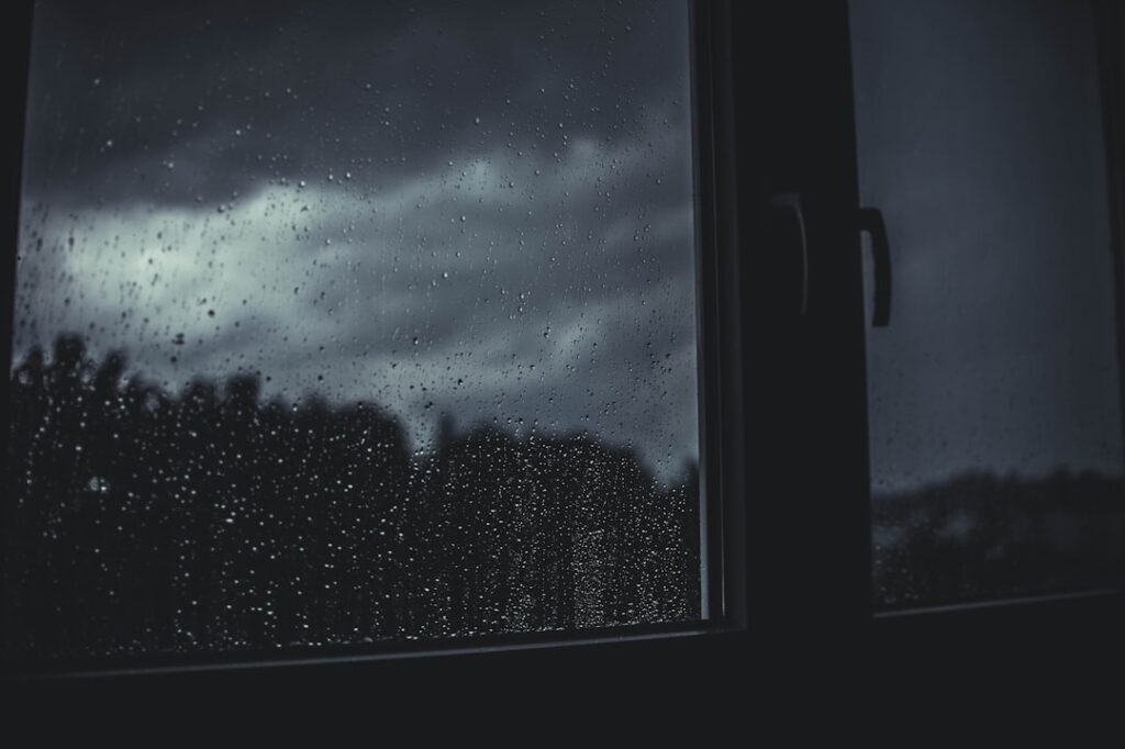 A figure by a rain-streaked window — illustrating harassment and protection orders in Singapore